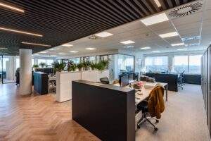 Modern kantoorinterieur aan het Koningin Wilhelminaplein met bureaus, planten en uitzicht over de stad.